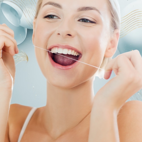 Smilende lyshåret kvinde bruger tandtråd mellem sine hvide tænder for at demonstrere korrekt tandpleje.